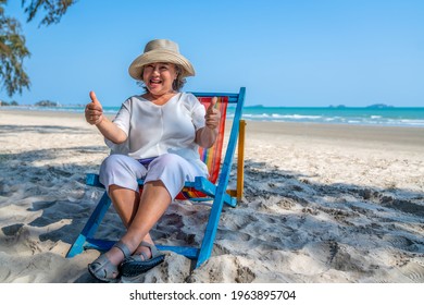 Healthy Asian senior woman resting on sunbed by the sea. Retirement elderly female sitting on beach chair relax and enjoy outdoor lifestyle activity at tropical island beach in summer holiday vacation - Powered by Shutterstock