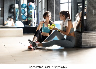 Healthy asian two people young woman eating vegetables green salad at gym In a room with a window with natural light. Fitness and healthy food concept