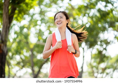 Healthy Asian Woman Running In The Park. She Smiled And Enjoyed.