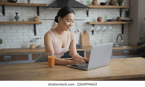 Healthy asian woman using laptop and drinking orange juice - Powered by Shutterstock