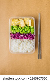 Healthy Asian-style Vegan Bento Box With Rice, Fried Tofu, Edamame Beans And Red Cabbage And Metal Chopsticks On Side, Flatlay