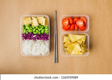 Healthy Asian-style Vegan Bento Box With Rice, Fried Tofu, Edamame Beans And Cherry Tomatoes And Pieces Of Pineapple With Metal Chopsticks On Side, Flatlay