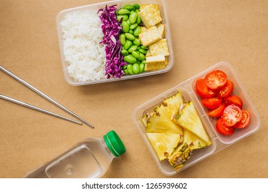 Healthy Asian-style Vegan Bento Box With Rice, Fried Tofu, Edamame Beans And Cherry Tomatoes And Pieces Of Pineapple With Metal Chopsticks On Side, Flatlay