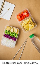 Healthy Asian-style Vegan Bento Box With Rice, Fried Tofu, Edamame Beans And Cherry Tomatoes And Pieces Of Pineapple With Metal Chopsticks On Side, Flatlay