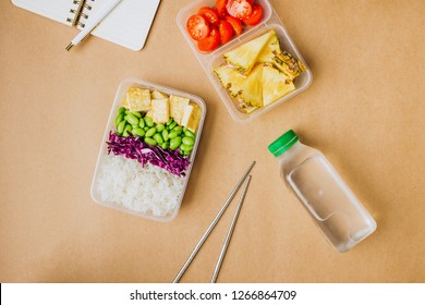 Healthy Asian-style Vegan Bento Box With Rice, Fried Tofu, Edamame Beans And Cherry Tomatoes And Pieces Of Pineapple With Metal Chopsticks On Side, Flatlay