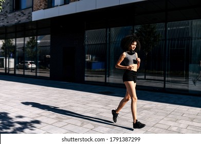 Healthy and athletic African woman running on the city street. A biracial girl is jogging in the morning. Full length - Powered by Shutterstock