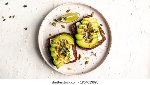 Healthy avocado toasts for breakfast or lunch with rye bread, sliced avocado, cheese, pumpkin and sesame seeds. banner, catering menu recipe top view. - Powered by Shutterstock