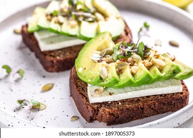 Healthy Avocado Toasts With Rye Bread, Sliced Avocado, Cheese, Pumpkin, Nut And Sesame For Breakfast Or Lunch. Vegetarian Food. Vegan Menu. Food Recipe Background. Close Up.