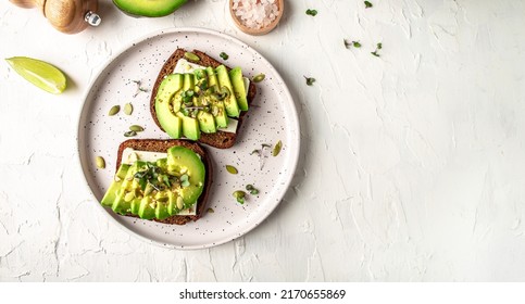 Healthy avocado toasts with rye bread, sliced avocado, cheese, pumpkin, nut and sesame for breakfast or lunch. Vegetarian food. Vegan menu. Food recipe background. Close up. - Powered by Shutterstock