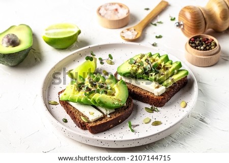 Healthy avocado toasts with rye bread, sliced avocado, cheese, pumpkin, nut and sesame for breakfast or lunch. Vegetarian food. Vegan menu. Food recipe background. Close up.