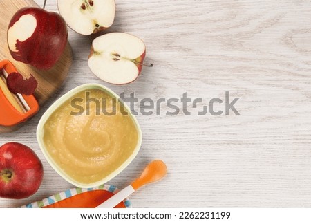 Healthy baby food. Bowl with delicious apple puree and fresh fruits on white wooden table, flat lay. Space for text