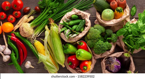 Healthy background with fresh different vegetables in reusable paper bags on wooden background