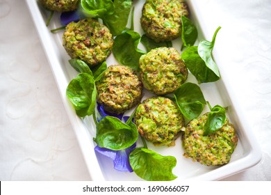 Healthy Baked Broccoli Tots With Raw Leafy Green, Serves On Ceramic White Plate, On Imbrodier White Placemat.