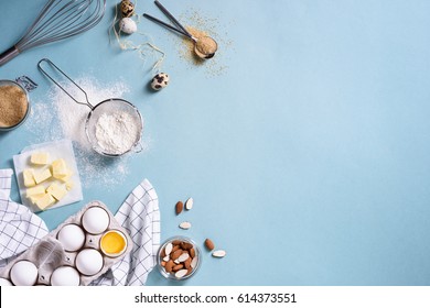 Healthy baking ingredients - flour, almond nuts, butter, eggs, biscuits over a blue table background. Bakery background frame. Top view, copy space.