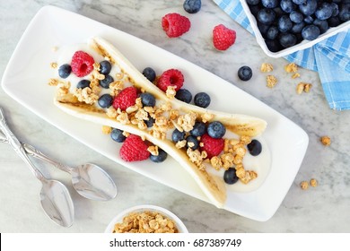 Healthy Banana Split With Yogurt, Fresh Berries And Granola, Overhead Scene On Marble