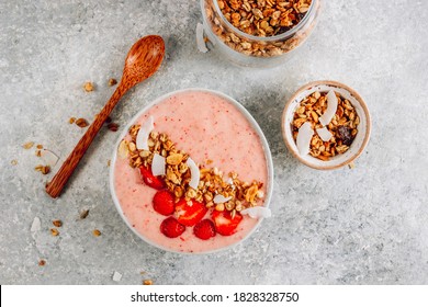 Healthy banana and strawberrie smoothie in a bowl with pieces of strawberries, granola and coconut chips on light gray background. Top view - Powered by Shutterstock