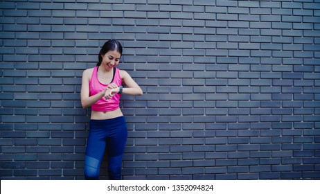 Healthy Beautiful Young Asian Athlete Woman Setting And Checking Progress Looking Heart Rate Monitor On Smart Watch While Running In Urban City. Lifestyle Women Exercise In The City Concept.