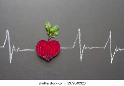 Healthy beetroot with heart shape and electrocardiogram on blackboard