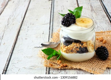 Healthy Blackberry And Banana Yogurt Parfait In A Mason Jar On A Rustic White Wood Background