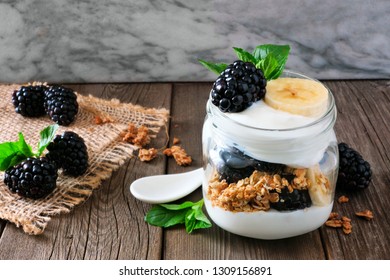 Healthy Blackberry And Banana Yogurt Parfait In A Mason Jar. Still Life On Dark Rustic Background.