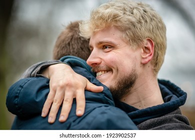 Healthy blonde man living with HIV hugging his friend outside at a park in Hamburg, Germany