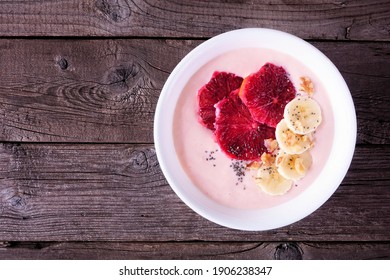 Healthy Blood Orange And Banana Smoothie Bowl With Walnuts And Chia Seeds. Overhead View On A Dark Wood Background.