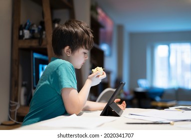 Healthy boy eating red apple for his snack after finished homework,New normal life kid using tablet for home learning,E-learning, Home schooling education, Back to school concept