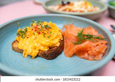 Healthy breakfast from 3 scrambled eggs, smoked salmon, wholemeal sourdough bread and lemon balm