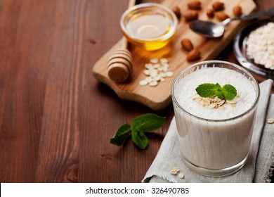 Healthy Breakfast Of Banana Smoothie Or Milkshake With Oats And Honey Decorated Mint Leaves On Rustic Surface