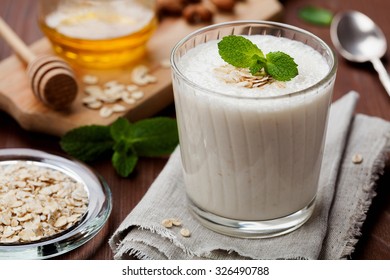 Healthy Breakfast Of Banana Smoothie Or Milkshake With Oats And Honey Decorated Mint Leaves On Rustic Surface