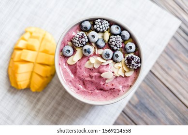 Healthy Breakfast Berry Smoothie Bowl Topped With Blueberries Blackberries, Pumpkin Seeds And Almond Flakes With Copyspace. Delicious Mango Smoothie Bowl. Vegan Raw Food. Selective Focus. Flatlay