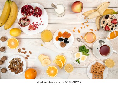 Healthy Breakfast. Boiled Eggs, Muesli, Orange Juice, Cup Of Tea, Yogurt, Honey, Nuts And Fresh Fruits On White Table. Healthy Organic Natural Food Concept. Top View. View From Above.