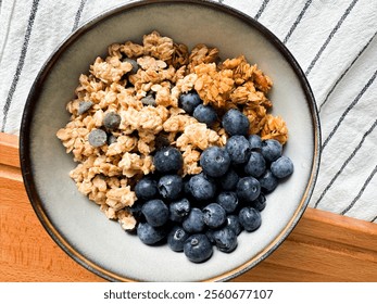 Healthy breakfast bowl with granola and fresh blueberries on a wooden surface - Powered by Shutterstock