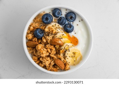 Healthy breakfast. Bowl of greek yogurt with oat granola, fruits, nuts, honey and chia seeds. Top view. Diet food