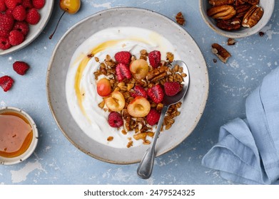 Healthy breakfast. Bowl with Greek yogurt, granola, raspberries, cherries and nuts. Healthy eating concept. Top view - Powered by Shutterstock