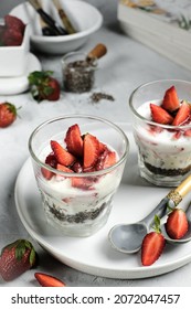 healthy breakfast consists of chiaseed pudding with strawberries and youghurt, served in two glasses on white olate over whute rustic backgroud. Sugar free strawberries chia seed puddings
