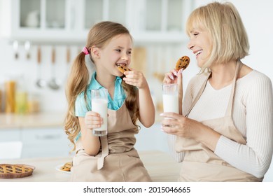 Healthy Breakfast. Cute Little Girl And Her Smiling Grandmother Eating Homemade Cookies Holding Glasses Drinking Milk Looking At Each Other. Time For Vitamins And Nutrition Concept, Selective Focus