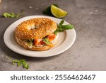 Healthy breakfast food. Bagel sandwich with salmon, cream cheese, cucumber and microgreens on gray background. Burger with salmon.