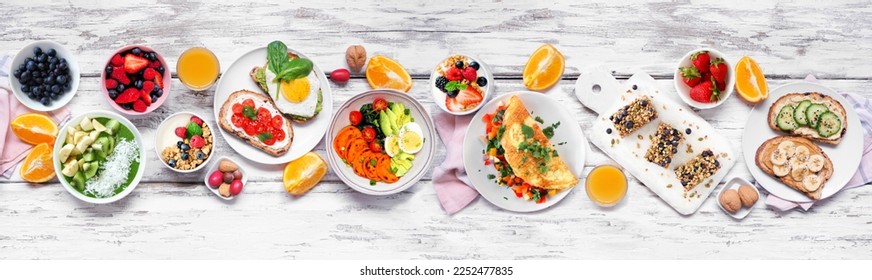 Healthy breakfast food table scene. Top down view over a white wood banner background. Omelette, nutritious bowl, toasts, granola bars, smoothie bowl, yogurts and fruits. - Shutterstock ID 2252477835