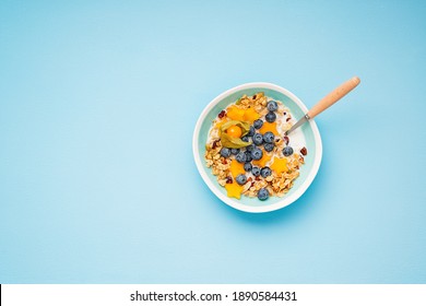 Healthy breakfast. Fresh granola, muesli with milk, honey and berries. Blue color background.Top view