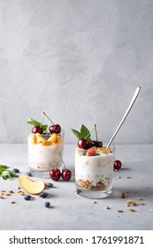 Healthy breakfast in a glass with fresh fruits: pomegranate, cherry, nectarines, honeysuckle, yogurt and granola on a grey background. Shallow depth of field with selective focus - Shutterstock ID 1761991871