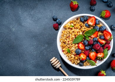 Healthy breakfast granola with fresh berry - strawberry, raspberry, blueberry on black background