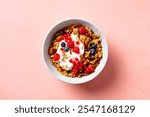 Healthy breakfast. Granola, muesli with yogurt and fresh berries. Pink background. Top view.