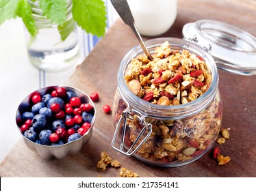 Healthy breakfast. Granola with pumpkin seeds and goji berries, honey, yogurt and fresh berries in a glass on blue and white background. - Powered by Shutterstock