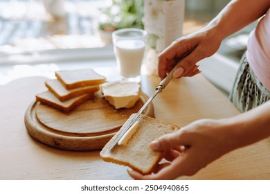 healthy breakfast milk bread and butter. young woman's hand spreading butter on slice of toasted bread, glass of fresh milk in background - Powered by Shutterstock