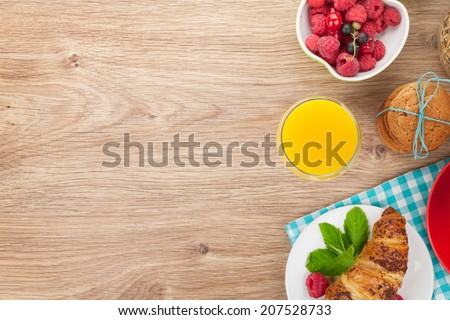 Healthy breakfast with muesli, berries, orange juice, coffee and croissant. View from above on wooden table with copy space