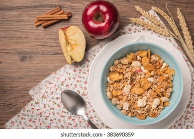 Healthy Breakfast With Muesli, Red Apple And Cinnamon On Rustic Wooden Table. Top View With Copy Space.