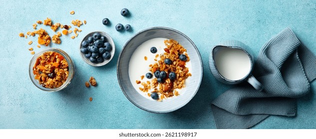 Desayuno saludable. Granola de avena con arándanos frescos y leche en un tazón. Fondo azul. Vista superior.