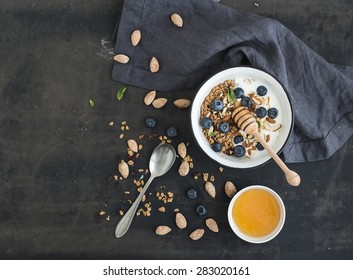 Healthy breakfast. Oat granola with fresh blueberries, almond, yogurt and mint in a rustic metal bowl over dark grunge surface. Top view, copy space - Powered by Shutterstock