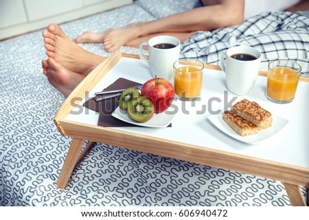 Gesundes Frühstück auf Tablett und Paar Beine im Hintergrund